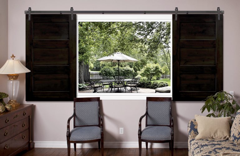 Sliding barn door shutters framing view of patio